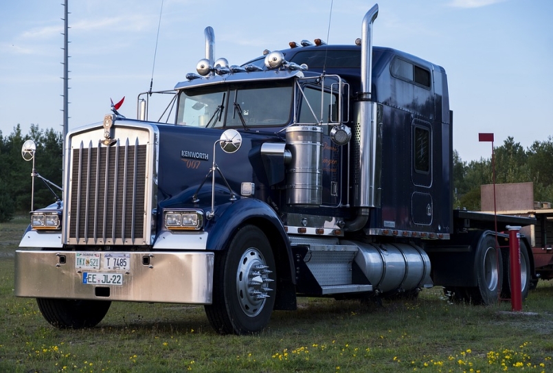 Large 18 wheeler truck.  The body is blue, it has 3 license plates and it is a Kenworth 007.